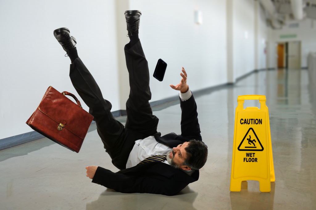 A businessman slipping and falling near a wet floor sign